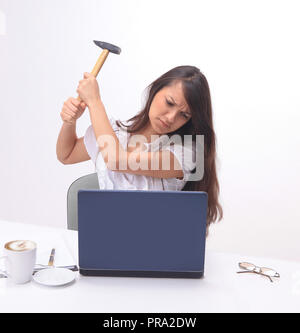 Young business woman smashing un laptop seduto dietro una scrivania. Foto Stock