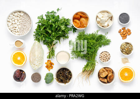 Fonte di calcio per i vegetariani. Cibo sano e pulito mangiare: frutta, verdura, semi, super, verdura a foglia su sfondo bianco vista superiore Foto Stock