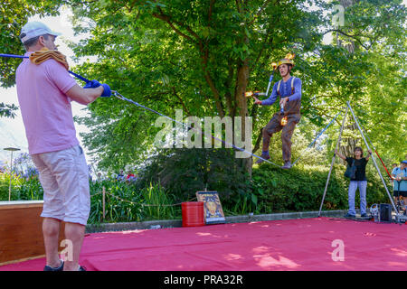 Lugano, Svizzera - 15 Luglio 2016 - uomo a camminare sulla slackline supportato da persone a Buskers Festival a Lugano, Svizzera Foto Stock