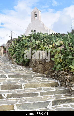 Grecia, l'affascinante isola di Sikinos. Un sentiero a gradini si innalza dolcemente verso una vecchia, bella, bianca cappella greca. Foto Stock