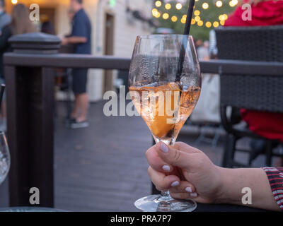 Donna che mantiene piena a metà spritz drink in un bicchiere all'aperto presso un ristorante Foto Stock