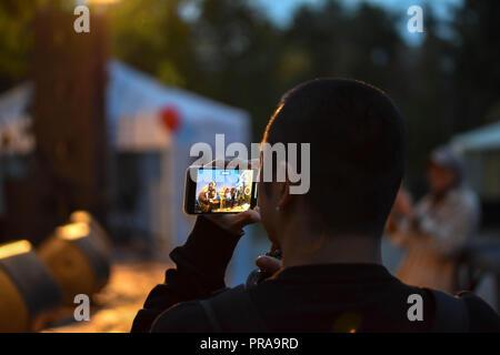 Giovane uomo asiatico facendo una registrazione video di un concerto live show sul suo smartphone Foto Stock