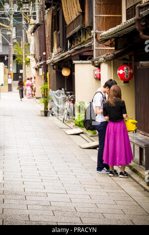 Un giovane guardando qualcosa mentre si cammina per le strade del quartiere di Gion vecchia Kyoto, Giappone Foto Stock