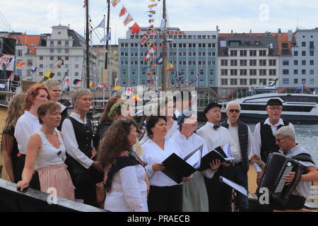 Un coro canta tradizionali canzoni norvegesi sul ponte di una nave nel porto di Bergen, Norvegia, durante il giorno di mercato (Torgdagen). Foto Stock