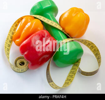 Nastro di misurazione e pepe su uno sfondo bianco. Manubri Fitness Foto Stock