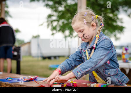 Adorabile ragazza bionda a giocare con un gioco di pasta e di creazione di figura sul tavolo Foto Stock