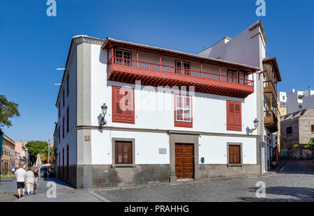 TENERIFE, Spagna - 20 agosto: turisti camminare accanto a una tipica casa delle Canarie a Plaza de la Iglesia piazza di Santa Cruz de Tenerife Il 20 agosto 2018 a Tenerife, Spagna. Balconi in legno sono molto spesso visto nella capitale dell'isola. Foto Stock