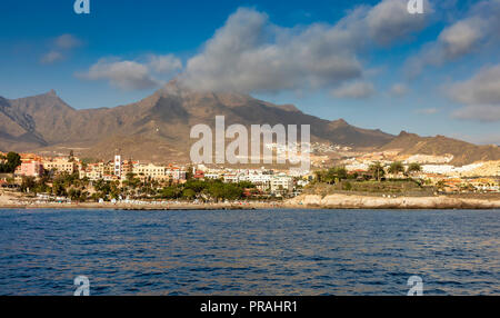 TENERIFE, Spagna - 21 agosto: (nota del redattore: un filtro polarizzante è stato utilizzato per questa immagine.) La Roque del Conde mountain è visto dietro il Playa El Duque Beach a Costa Adeje il 21 agosto 2018 a Tenerife, Spagna. Costa Adeje è una delle destinazioni turistiche più popolari presso la costa meridionale dell'isola. Foto Stock