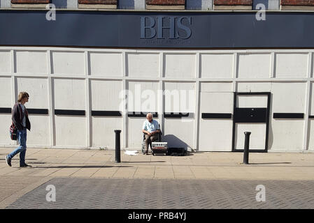 Fotografia di strada di un busker fuori ora chiuso casa britannica archivia il ramo a Lincoln, Regno Unito immagine presa su uno smartphone. Foto Stock