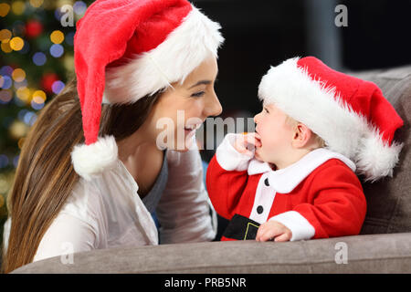 Felice la madre e il bambino alla ricerca di ogni altro nel natale giacente su un divano nel salotto di casa Foto Stock