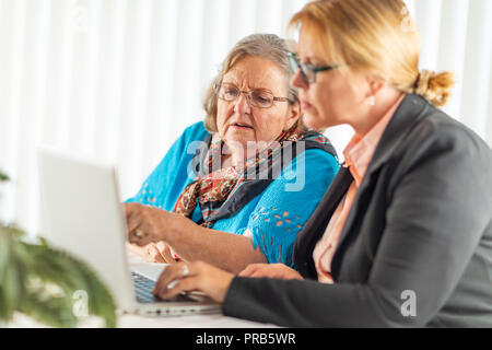 La donna aiuta adulti Senior Lady sul computer portatile. Foto Stock