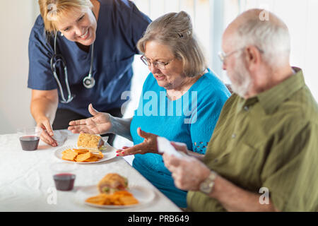 Donne medico o infermiere che serve Senior Adulto Giovane sandwiches nella tabella. Foto Stock