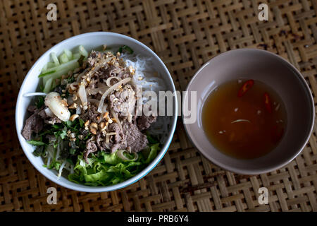 Close-up di una ciotola di vietnamiti noodle soup Pho Bun Bo Hue con carne e salsicce di maiale farcita con un fresco e tagliare il peperoncino e cipolline Foto Stock