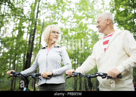 Età matura in activewear di decidere dove andare a fare escursioni in bicicletta sul giorno di estate Foto Stock