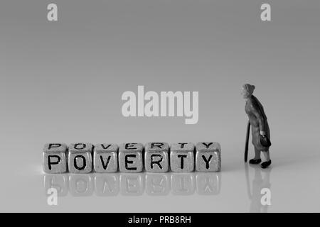 Scala in miniatura modello donna senior titolare di pensione o di rendita a piedi con un bastone con la parola povertà su sfere Foto Stock