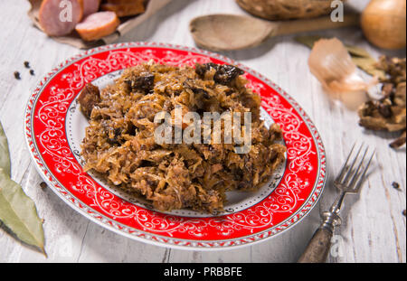 Cavolo nero stufato con carne, funghi e prugne secche - piatto tradizionale polacca Foto Stock