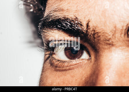 Macro shot del giovane uomo con gli occhi: l'occhio umano lateralmente, Close-up, isolati su sfondo bianco Foto Stock