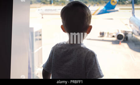 Silhouette di poco il toddler boy cercando in atterraggio aereo presso l'aeroporto internazionale Foto Stock