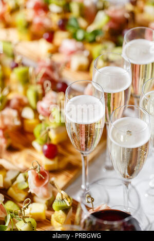Il buffet presso la reception. Bicchieri di vino e champagne. Assortimento di tartine sulla tavola di legno. Servizio banchetti. catering food, snack al formaggio, prosciutto, prosciutto e frutta Foto Stock