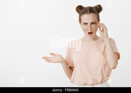 Ragazza audizione sciocchezze, aventi argomento, essendo dispiaciuto quello che si sente. Intensa perplesso ragazza in abiti alla moda, tenuto spento eyewear, gesticolando sollevato palm in clueless espressione confusa Foto Stock