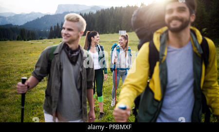 Gruppo di amici sono le escursioni in montagna. I giovani a piedi attraverso la campagna. Foto Stock