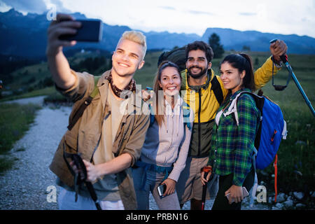 Turismo, viaggio, escursione e concetto di persone - happy gruppo di amici prendendo selfie e escursionismo Foto Stock