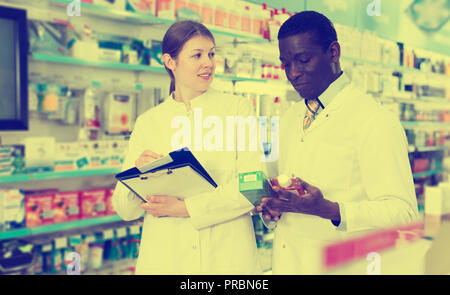 Vissuto adulto maschio e femmina di farmacisti, inventario di medicine in farmacia Foto Stock