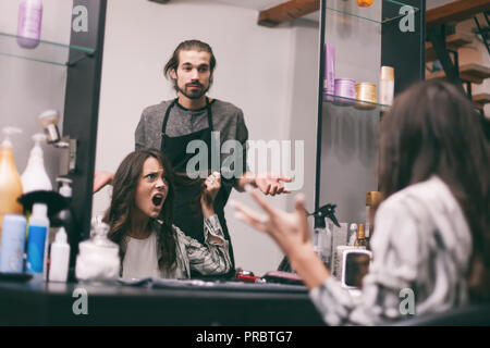 Giovane donna getting nuova acconciatura di capelli professionale salone di acconciatura. Lei non è soddisfatto con la sua nuova acconciatura. Foto Stock