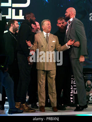 Deontay Wilder (sinistra) e Tyson Fury (destra) reagiscono come promotore Frank Warren (centro) li tiene separati nel corso di una conferenza stampa a BT Sport Studio, Londra. Foto Stock