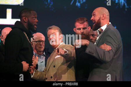 Deontay Wilder (sinistra) e Tyson Fury (destra) reagiscono come promotore Frank Warren (centro) li tiene separati nel corso di una conferenza stampa a BT Sport Studio, Londra. Foto Stock