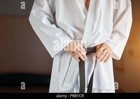 Le mani di serrare la cintura nera sull'uomo vestito di kimono Foto Stock