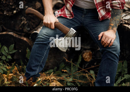 Uomo seduto su firewoods. Il taglialegna con ax riposo dopo il lavoro Foto Stock