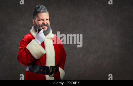 Babbo Natale con un'acconciatura e un sigaro lancia un fumo allegro Foto Stock