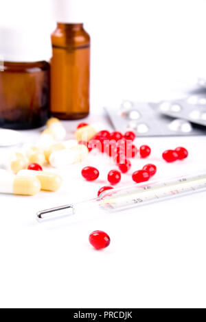 Termometro e diverse pillole closeup su sfondo bianco Foto Stock