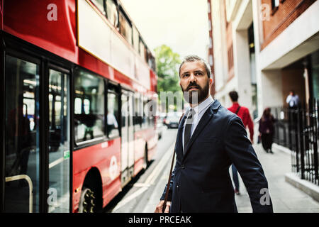 Hipster imprenditore permanente sulla strada, in attesa per il bus a Londra. Foto Stock