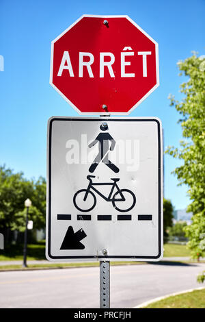 Il segnale di arresto (arret) in francese e un pedone e segno di bicicletta vicino a una strada a Montreal, Canada Foto Stock