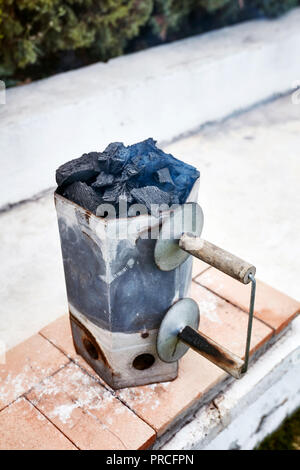 Smoking charcoal chimney starter bucket for barbecue in a backyard garden Foto Stock