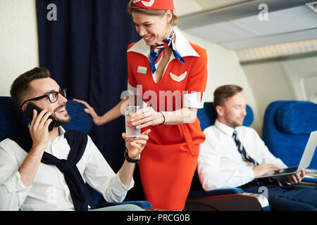 Assistente di Volo che serve bevande Foto Stock