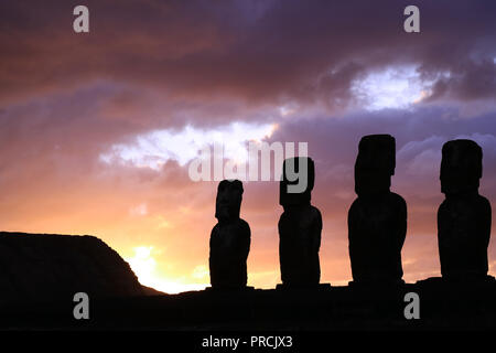 Stordimento viola Sunrise cielo nuvoloso oltre la sagoma del gigante Moai statue di Ahu Tongariki sito archeologico, Isola di Pasqua, Cile Foto Stock