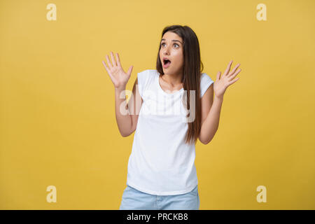 Bellissima femmina di metà lunghezza ritratto isolato su giallo studio backgroud. Il giovane sorride emotivo e sorpreso donna in piedi e guardando la telecamera.Le emozioni umane, espressione facciale concept Foto Stock