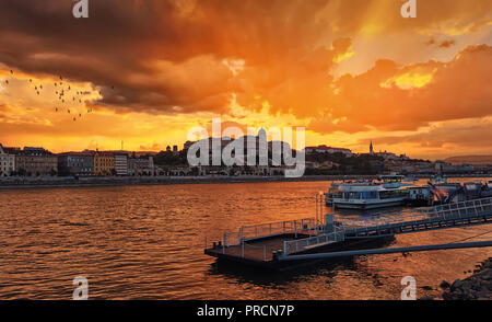 Vista del bellissimo tramonto dorato oltre il fiume Danubio, il Buda Hill e il Palazzo Reale di Pest. Foto Stock