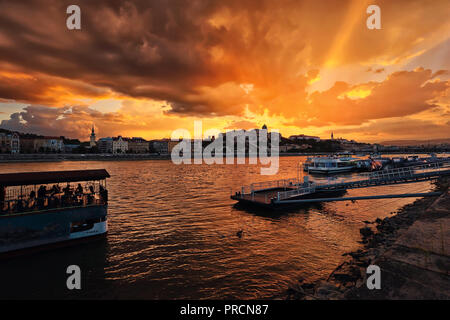 Vista del bellissimo tramonto dorato oltre il fiume Danubio, il Buda Hill e il Palazzo Reale di Pest. Foto Stock