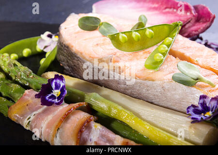 Cotto al forno salmone alla griglia, stick di asparago verde avvolto in pancetta su sfondo nero. Overhead. Foto Stock