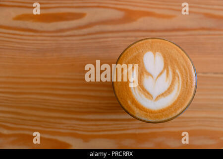Piatto bianco caffè vista dall'alto. Piatto bianco caffè in vetro trasparente su un tavolo di legno in una caffetteria. Esso è espresso in base a bere caffè costituito da espresso con microschiuma latte vaporizzato con bolle fini con una carta lucida o consistenza vellutata Foto Stock