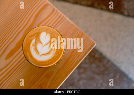Piatto bianco caffè sull'angolo del tavolo vista dall'alto. Piatto bianco caffè in vetro trasparente in un cafe.It è espresso in base a bere caffè costituito da espresso con microschiuma (latte vaporizzato con bolle sottili) Foto Stock