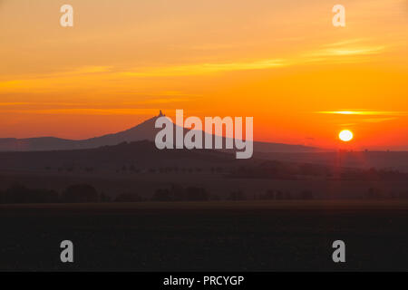 La silhouette di Hazmburk castello presso sunrise.Central Bohemian Uplands,Repubblica Ceca. Nella parte superiore della montagna vi è la rovina di un cast medievale Foto Stock