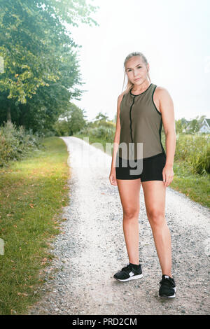 Bionda donna sportiva fa avanzare in posizione di parcheggio Foto Stock