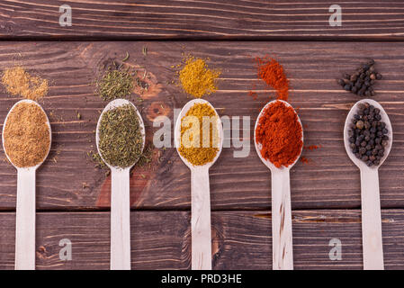 Assortimento di spezie colorate in i cucchiai di legno. Foto Stock
