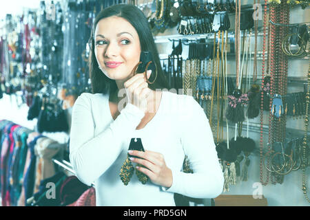 Felice sorridente ragazza positiva la scelta di moda orecchini nel negozio Gioielli Foto Stock