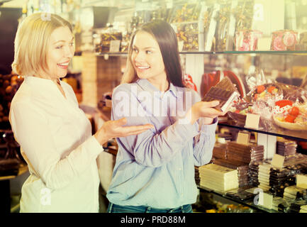 Femmina adulta clienti selezionando delizioso cioccolato al latte nel ripiano Foto Stock